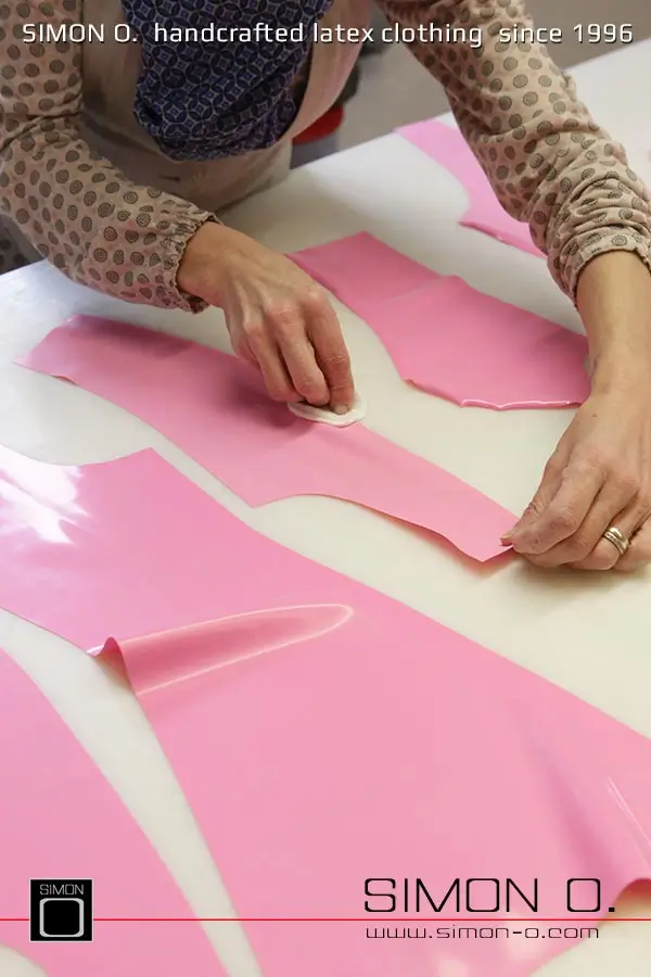 La production d'un catsuit en latex rose avec une partie transparente pour les jambes est montrée, en commençant par le découpage et le collage jusqu'au produit fini.