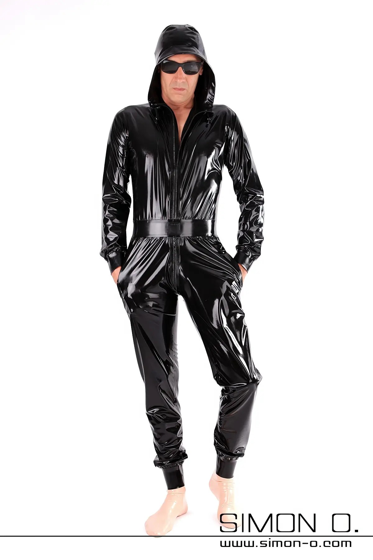 Latex Catsuit mit Kapuze und Taschen in Schwarz locker geschnitten aber tailliert mit Manschetten bei Armen und Beinen von vorne gesehen.
