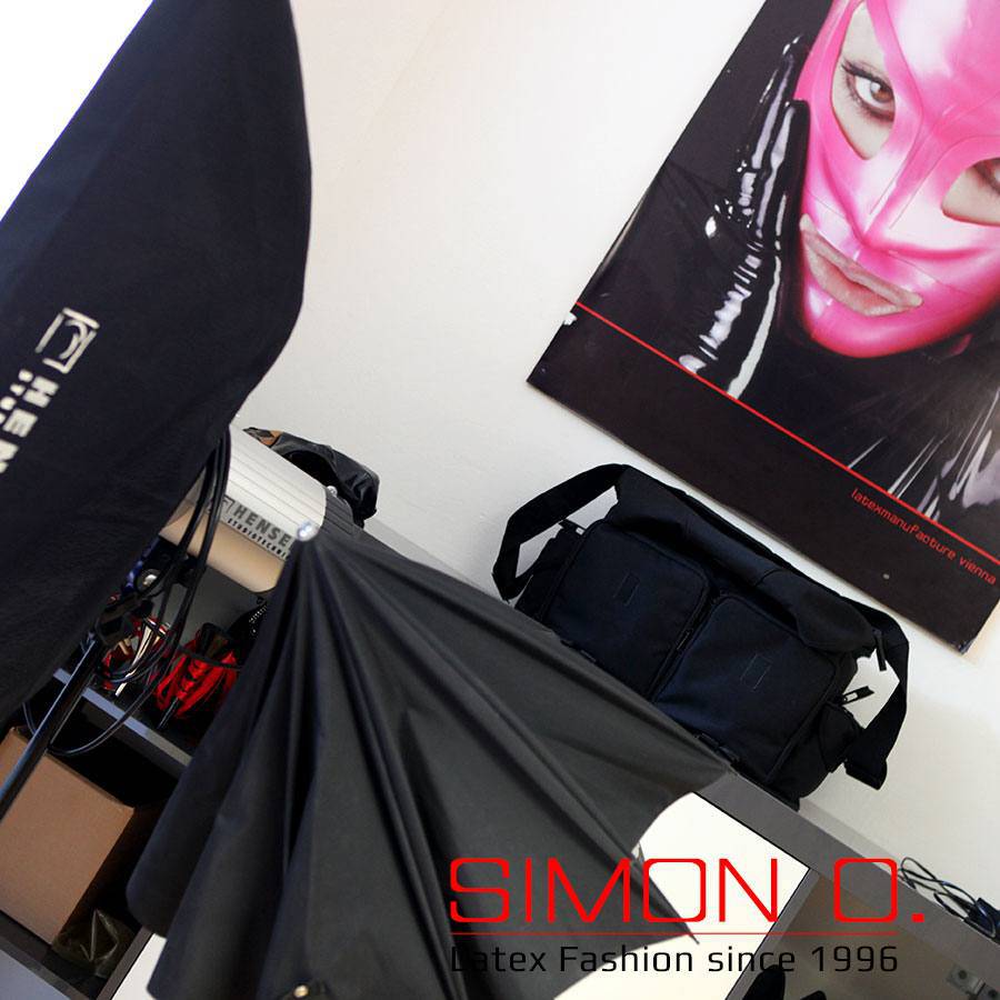 Latex Photo Studio A photo studio workstation with black bags, draped fabrics and a poster of a pink latex mask has been advertising SIMON O. Latex clothing.