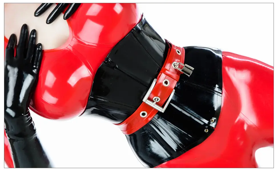 Person in einem rot-schwarz glänzenden Latex-Korsett mit passenden Handschuhen, die mit einer Hand im Gesicht und der anderen an der Taille posiert.