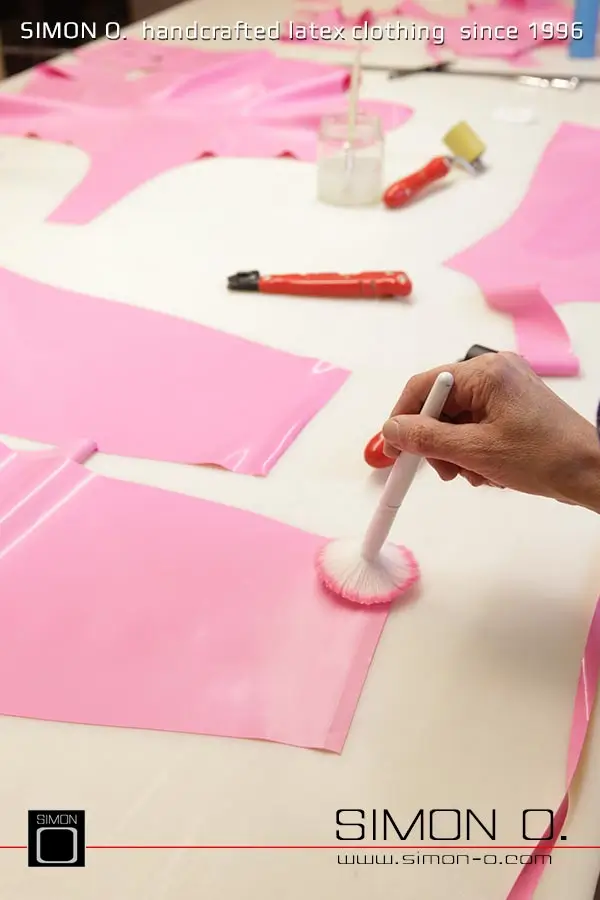 La production d'un catsuit en latex rose avec une partie transparente pour les jambes est montrée, en commençant par le découpage et le collage jusqu'au produit fini.