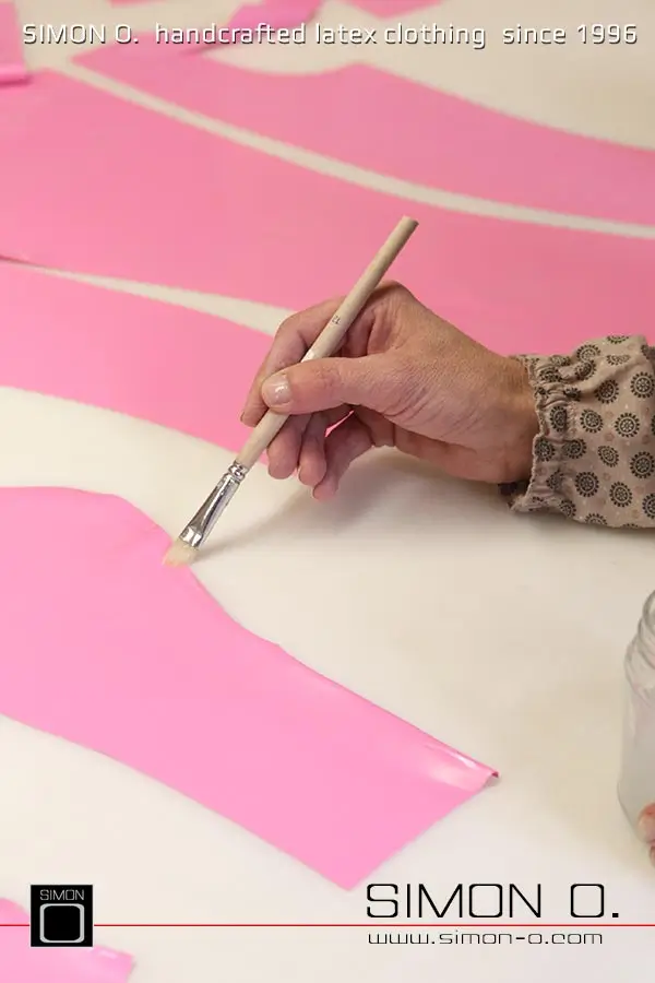 La production d'un catsuit en latex rose avec une partie transparente pour les jambes est montrée, en commençant par le découpage et le collage jusqu'au produit fini.