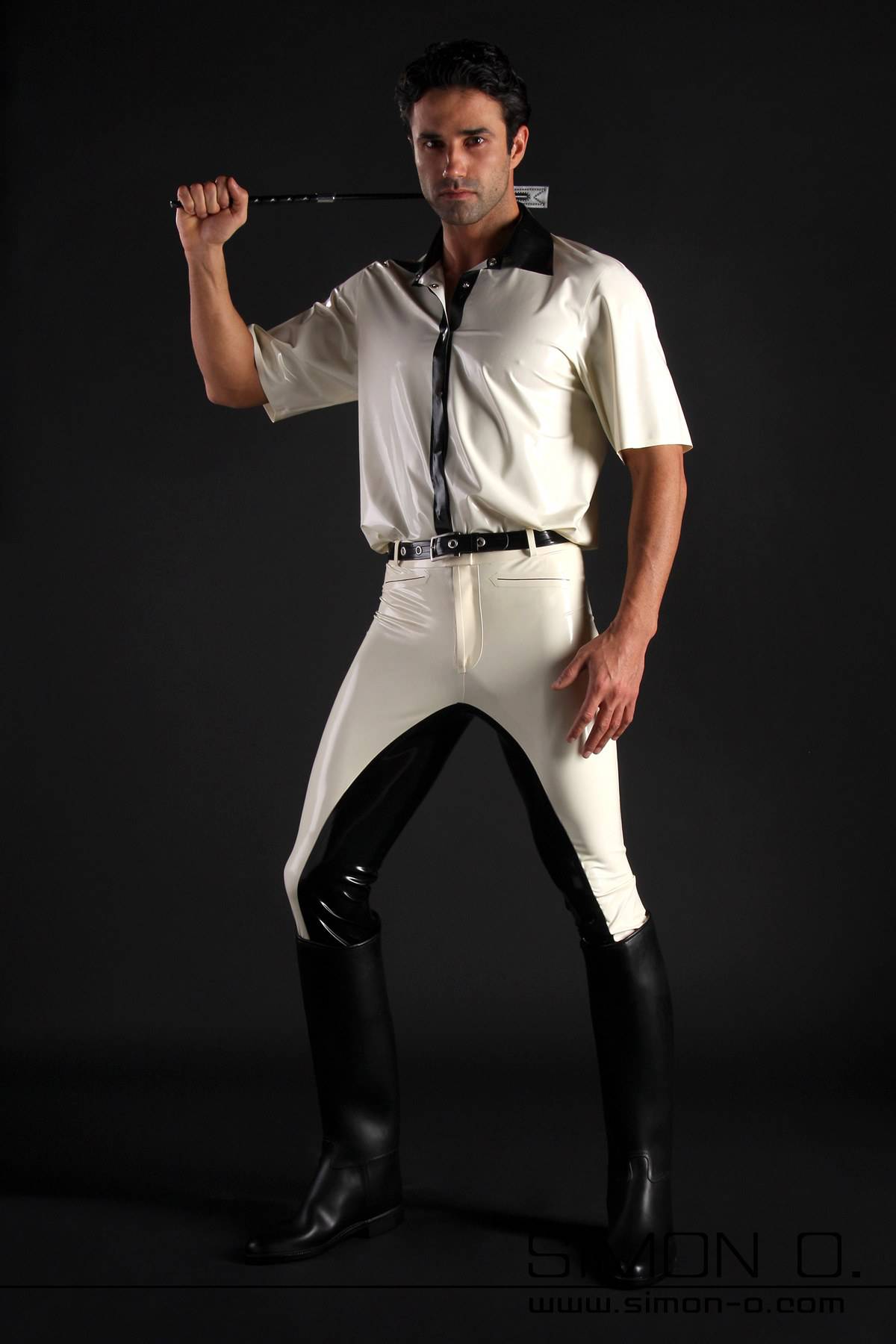 Latex riding breeches for men in black with white A man with a white latex shirt and a riding crop behind his head wears black and white latex breeches and riding boots.