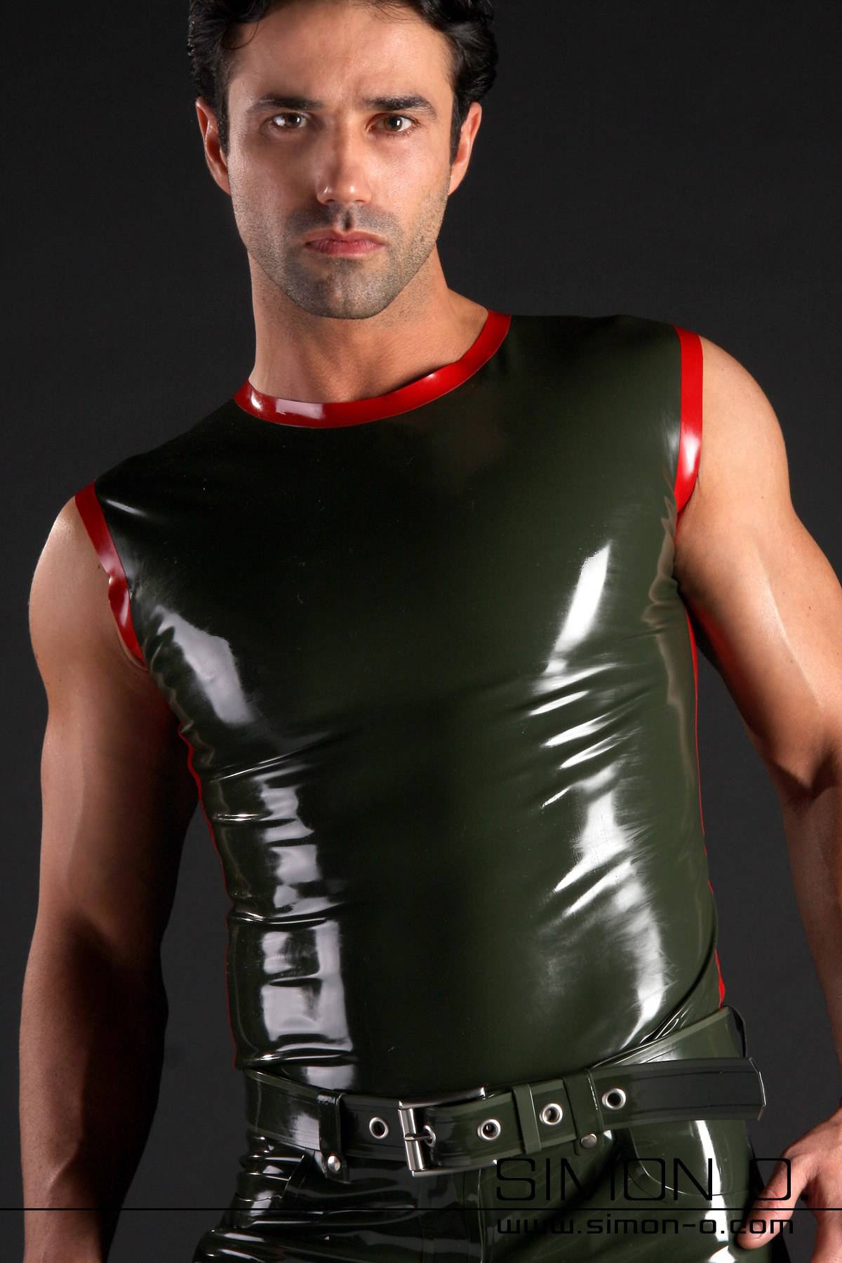 Men's Tank Top with Stripe A man wears a shiny dark green latex tank top with red trim and a black belt and stands confidently in front of a plain dark background.