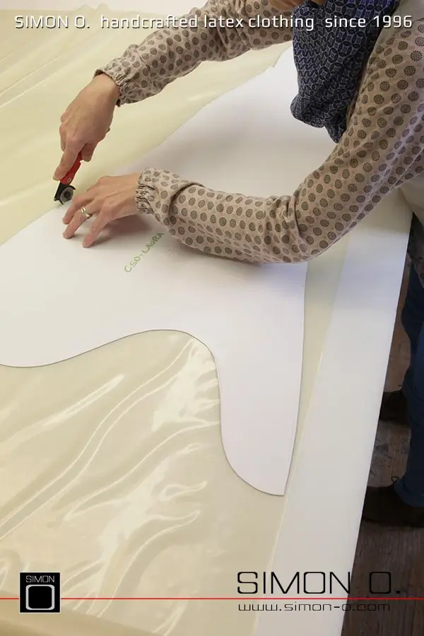 La production d'un catsuit en latex rose avec une partie transparente pour les jambes est montrée, en commençant par le découpage et le collage jusqu'au produit fini.