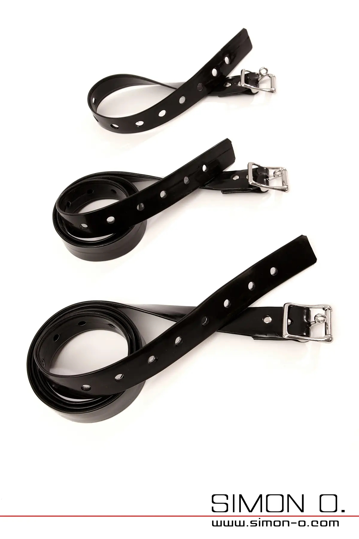 Schwarze Latex Fesselriemen mit absperrbarer silbernen Schnalle im Set,  mit Lochungen für Größenverstellung, aufgerollt auf weißem Hintergrund.