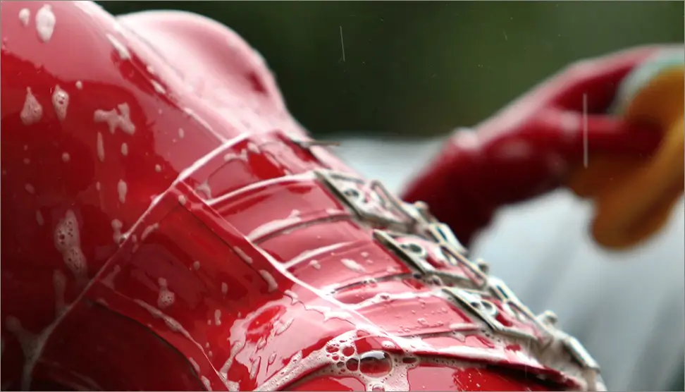 A person washes her red latex outfit while wearing it.