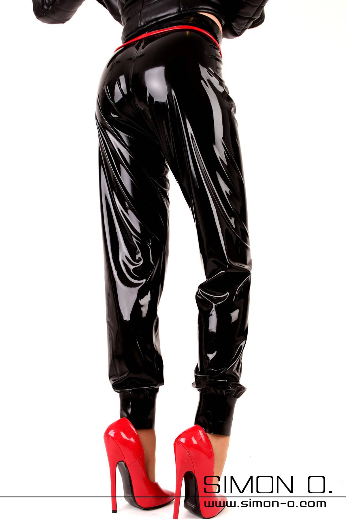 Glanz Jogginghose in Schwarz Eine Frau trägt eine Latex Glanz Joggingshose in Schwarz mit roten High Heels von hinten gesehen