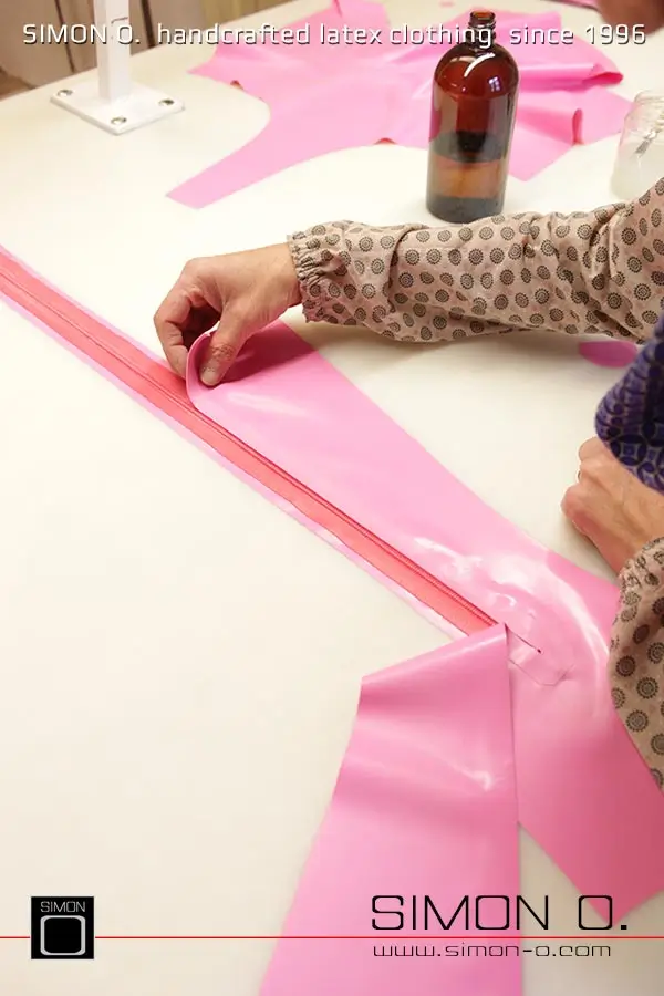 La production d'un catsuit en latex rose avec une partie transparente pour les jambes est montrée, en commençant par le découpage et le collage jusqu'au produit fini.