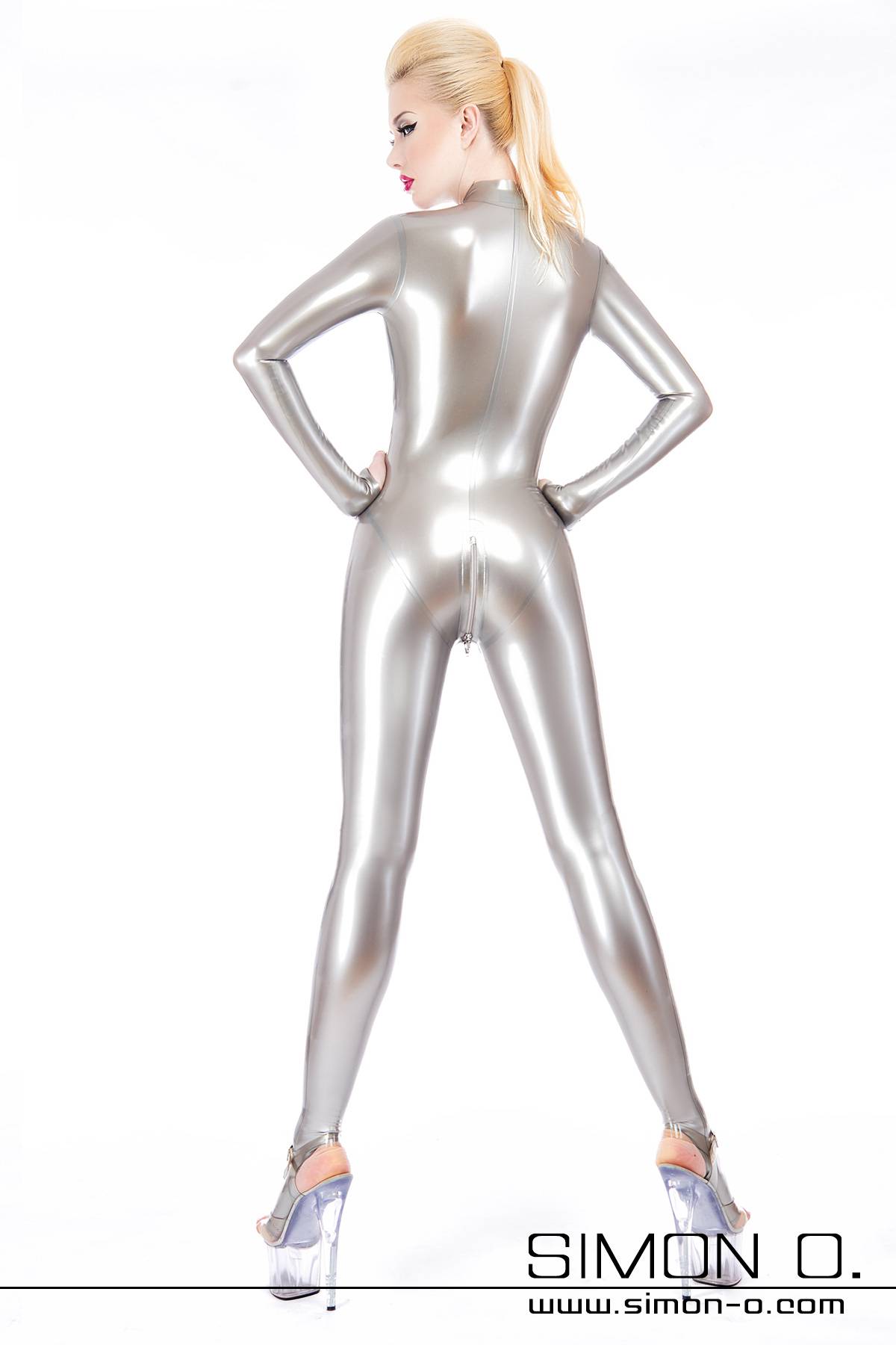 Latex catsuit in silver with crotch zip A blonde woman from behind in a skintight silver latex catsuit with zipper in the crotch area