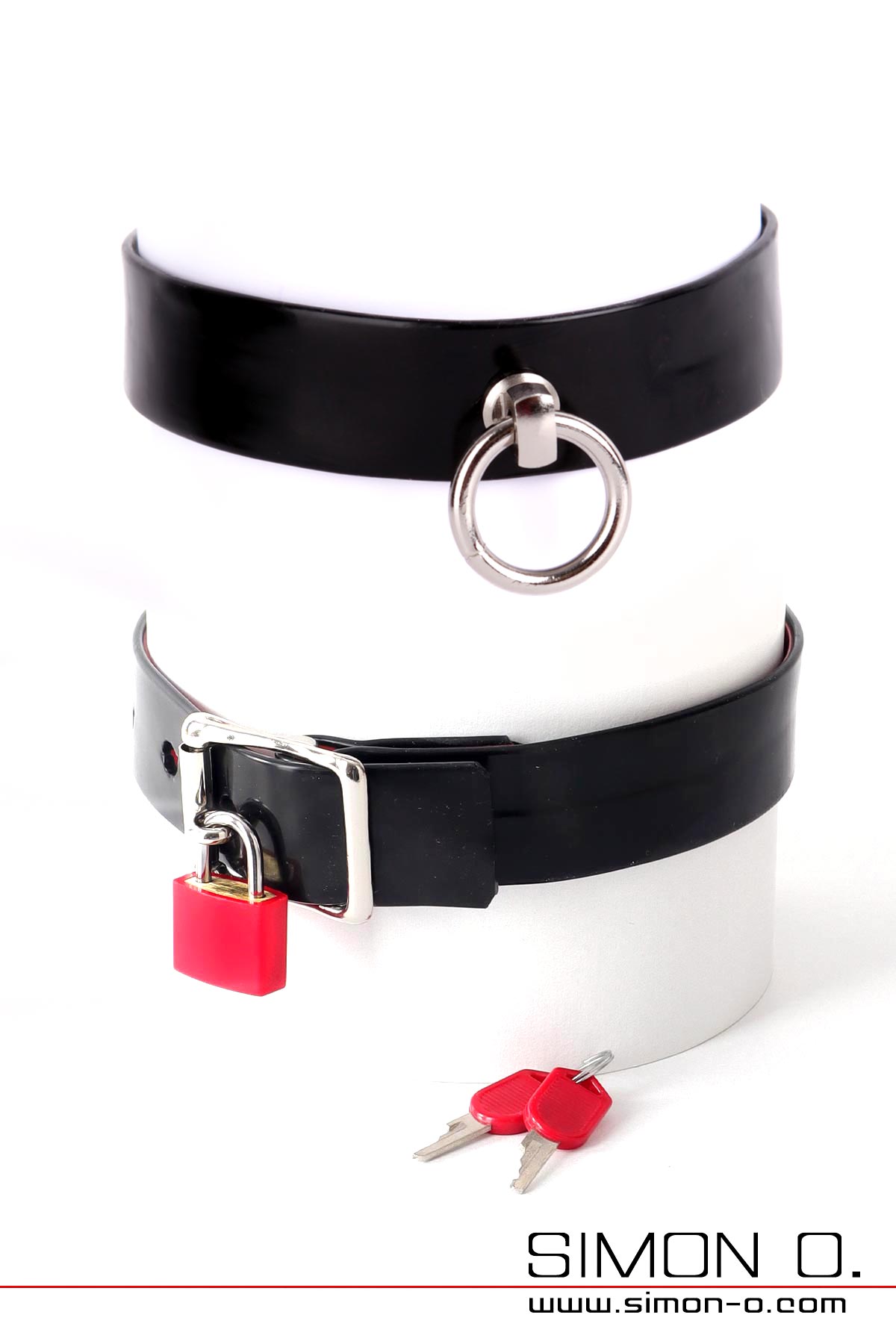 Latex Halsband mit dem Ring der O Latex Halsband in schwarz mit dem Ring der O und schwarz mit D-Ring. Die Rückseite zeigt eine mit einem Vorhängeschloss absperrbare Schnalle.