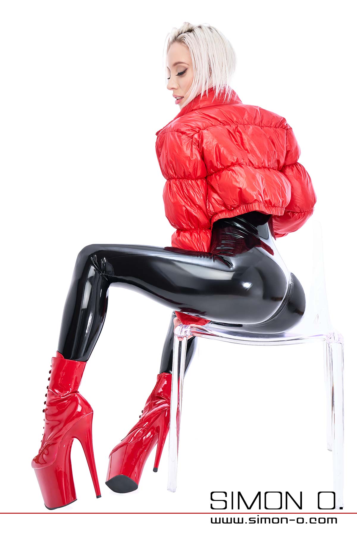 Latex Catsuit and down jacket A sexy lady wears a shiny black latex catsuit with a red down jacket and high heels.