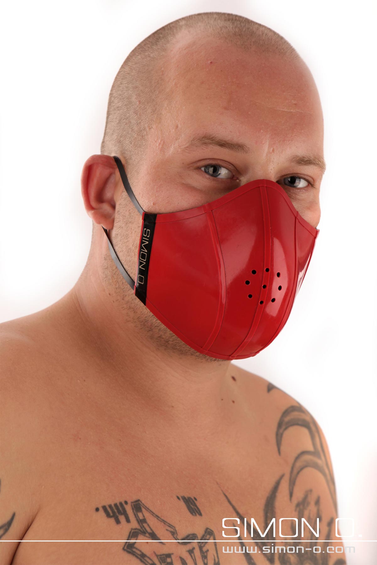Latex Mund und Nasenschutz in Rot Ein Mann mit Glatze trägt einen roten Mundschutz aus Latex.
