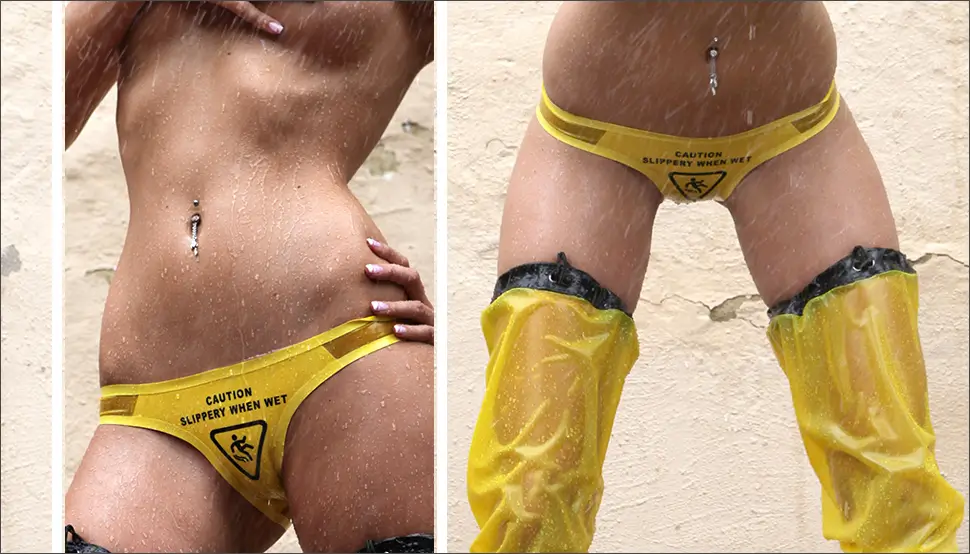 Latex briefs wetlook with text A person in yellow wet-look underwear with the inscription "Caution, slippery when wet", yellow boots and water splashing on her body, creating a playful slip atmosphere.