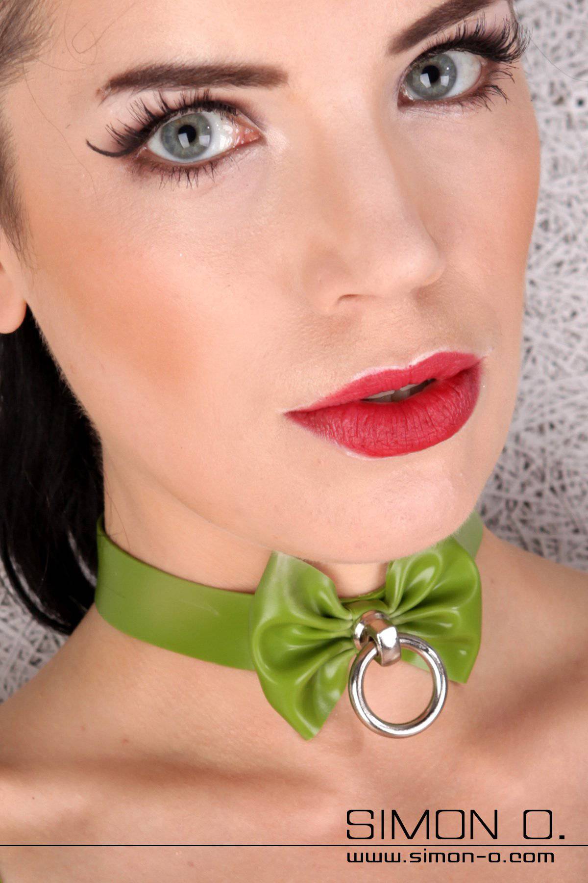 Latex Collar with Bow and O-Ring A woman with light make-up wears a green latex collar with bow and O-ring.