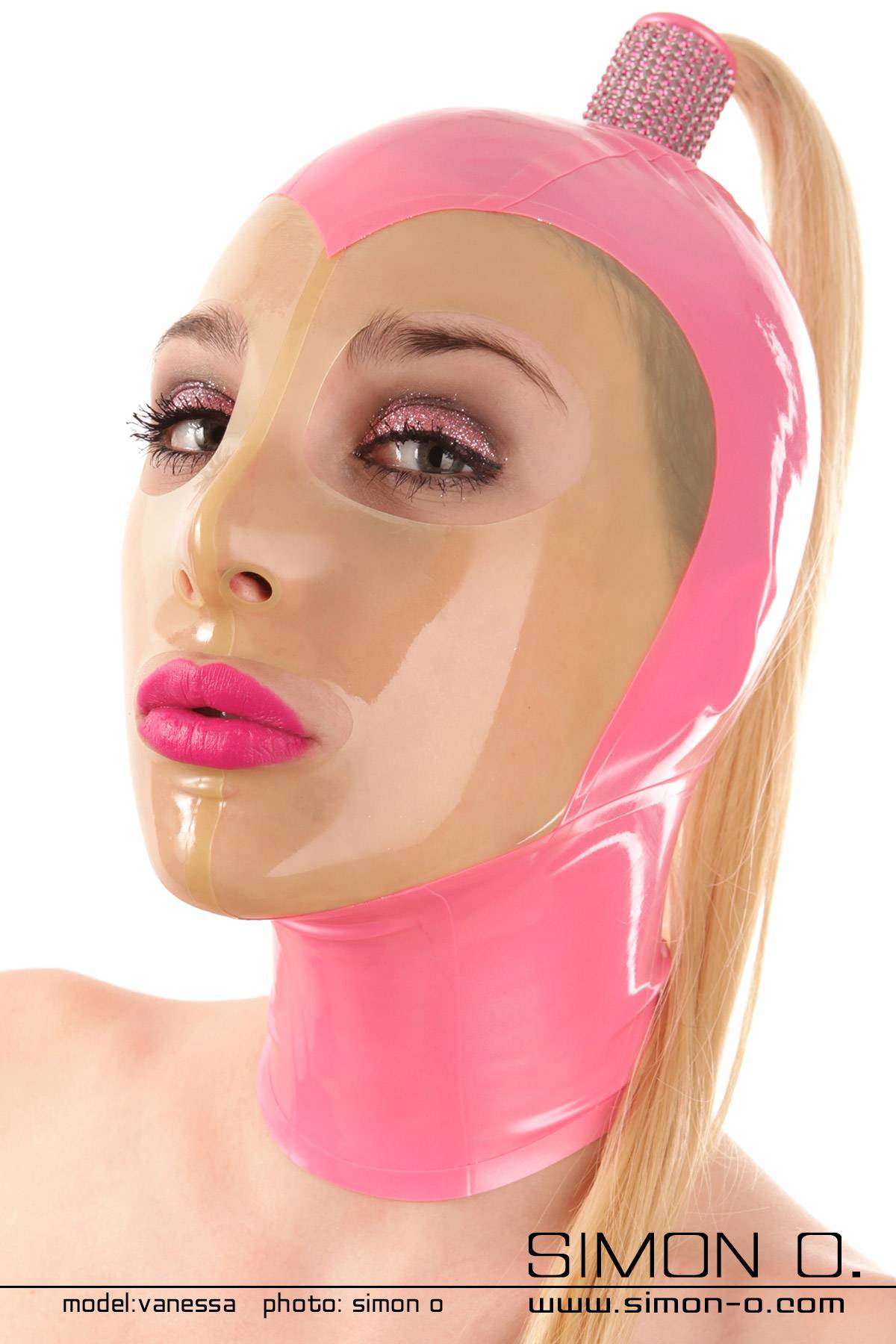 Latex Maske mit transparenten Gesichtsfeld und Ponytail Eine Person trägt eine rosa Latex Maske mit transparenten Gesichtsfeld und einem daran befestigten blonden Haarteil.