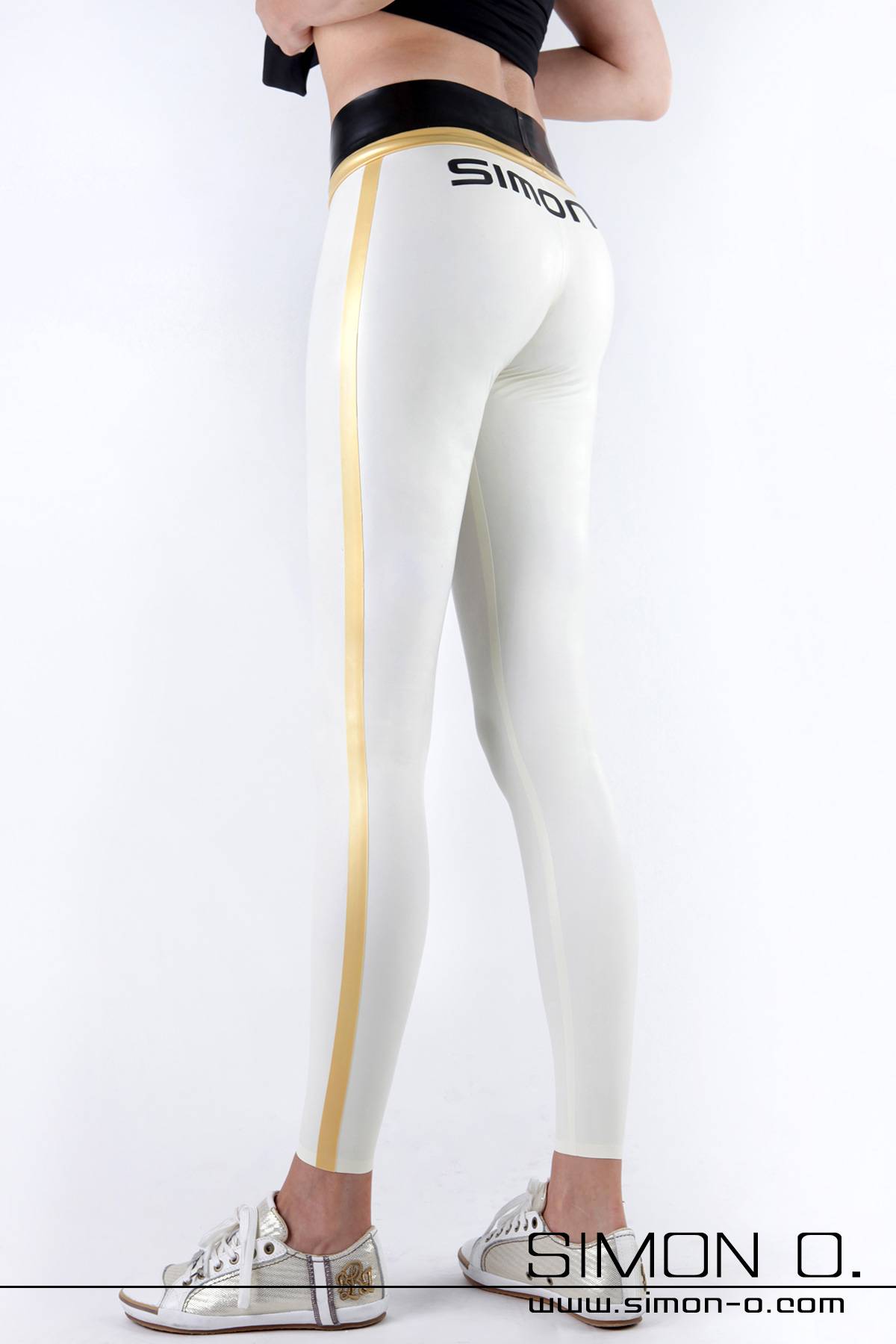 White latex leggings with gold stripes One person wears white latex leggings with gold side stripes, a black "SIMON O." waistband and white trainers and stands in front of a white background.