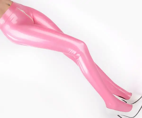 Eine Frau trägt eine glänzende rosa Latexstrumpfhose mit Reißverschluss im Schritt, gepaart mit weißen hochhackigen Schuhen. Der Schwerpunkt liegt auf den Beinen vor einem schlichten weißen Hintergrund.