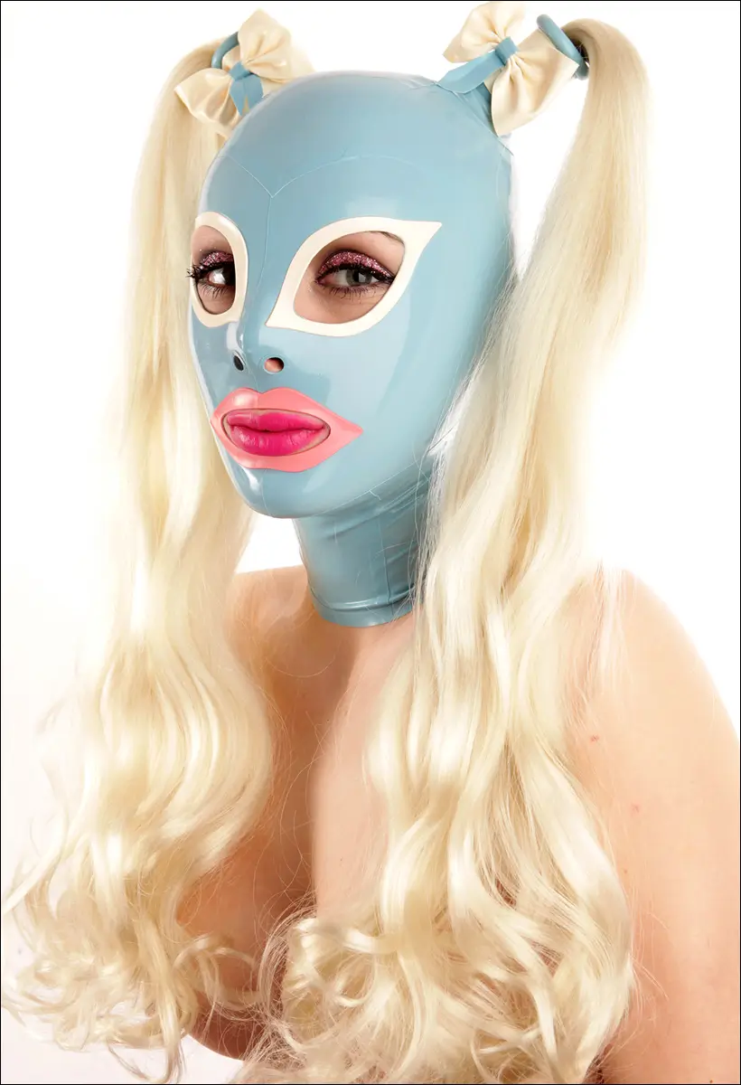 Eine Frau trägt eine glänzende, hellblaue Latexmaske mit weißen Augen- und rosa Munddetails. Die Maske hat blonde Zöpfe und cremefarbene Schleifen.