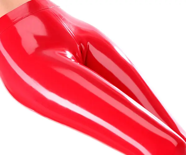 Das Bild zeigt eine Person in glänzenden, eng anliegenden roten Latex-Leggings und hebt die glänzende Textur und glatte Oberfläche des Materials hervor. Der Fokus liegt auf den Beinen von der Taille bis zu den Knöcheln, was die Verlockung der Latexmode no