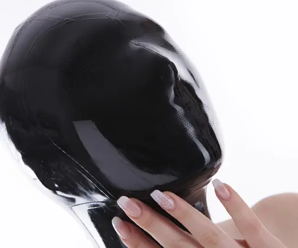 Eine Frau trägt einen schwarze komplett geschlossene Latex Maske. Diese Latex Maske hat aber unzählige kleine Perforationen durch welche man etwas sehen und atmen kann.