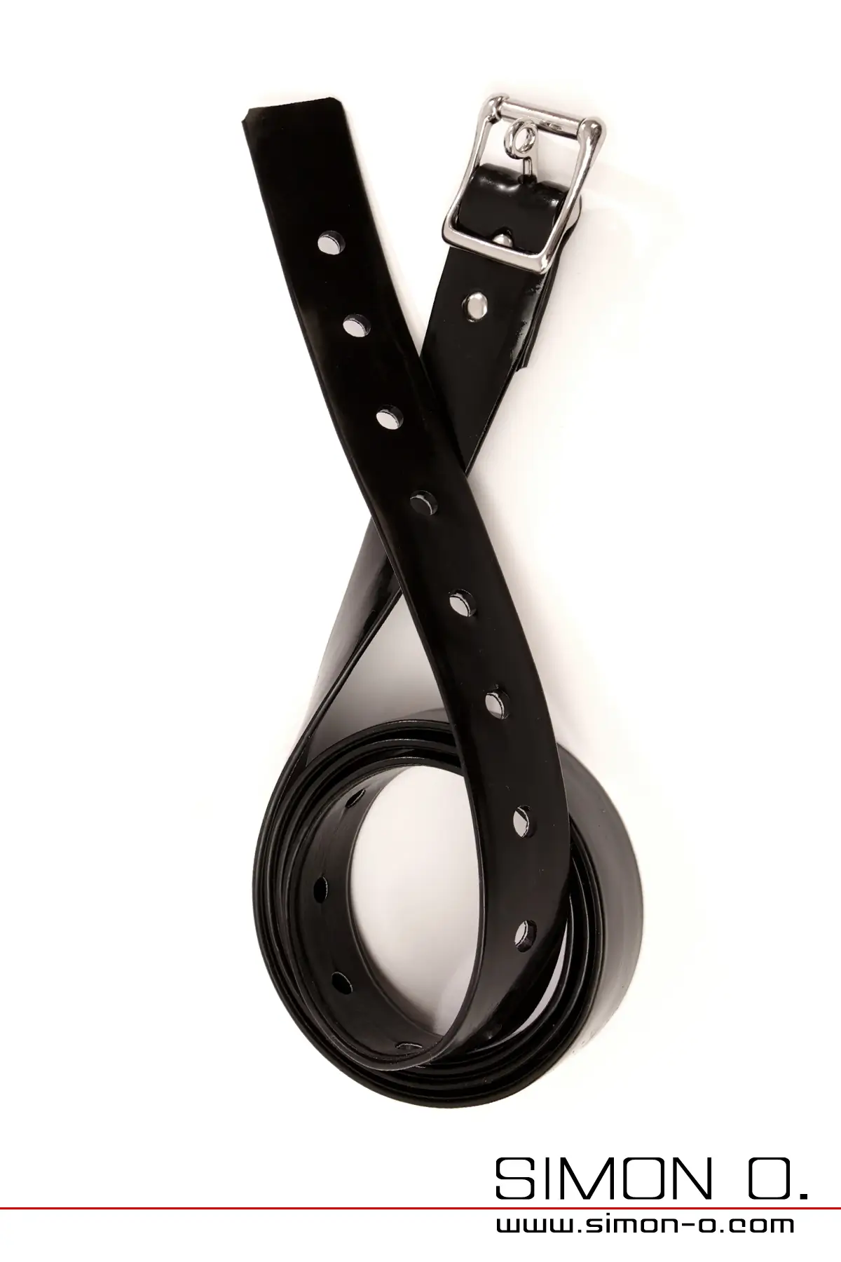 Une lanière de cheville en latex noir et brillant avec des trous et une boucle en métal, enroulée sur un fond blanc.