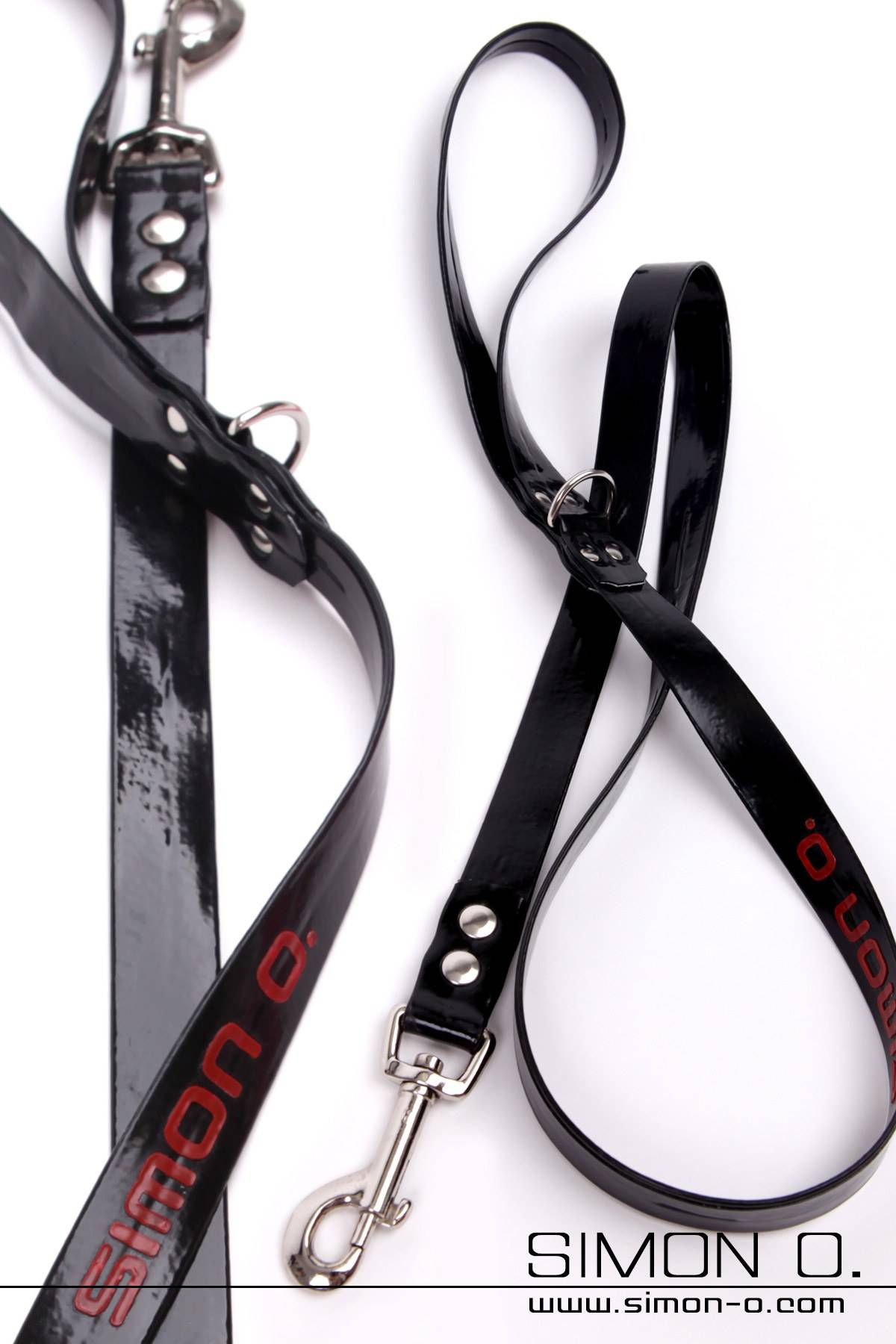 Latex Leine Schwarz Zwei schwarze Latex Leinen mit Metallverschlüssen sind auf weißem Hintergrund dargestellt. Auf einer Leine ist „SIMON O.“ in Rot aufgedruckt.