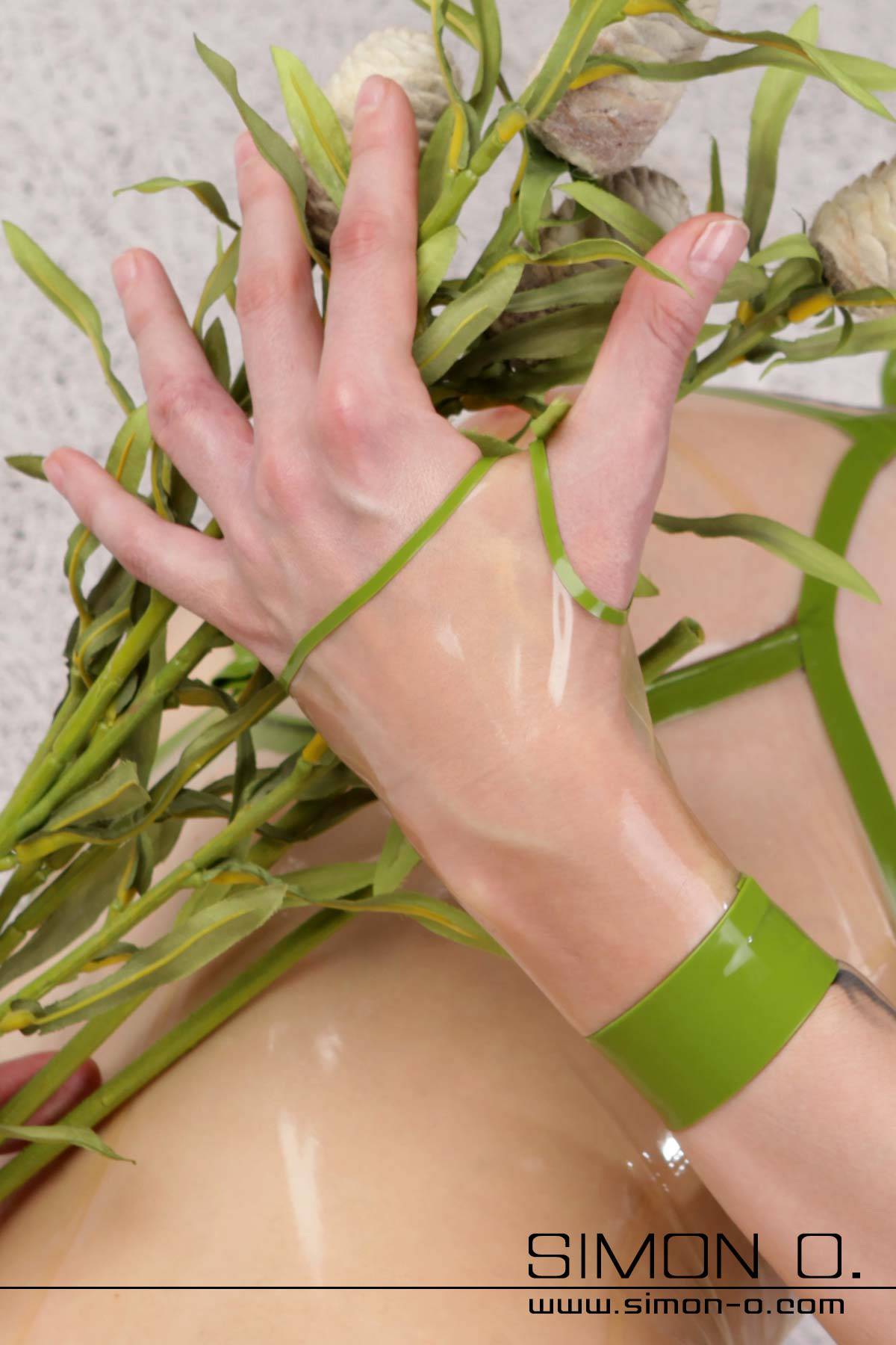 Short Latex Gauntlets One hand with a transparent short gauntlet holds a bouquet of green leaves. The glove is transparent with green appliqués.