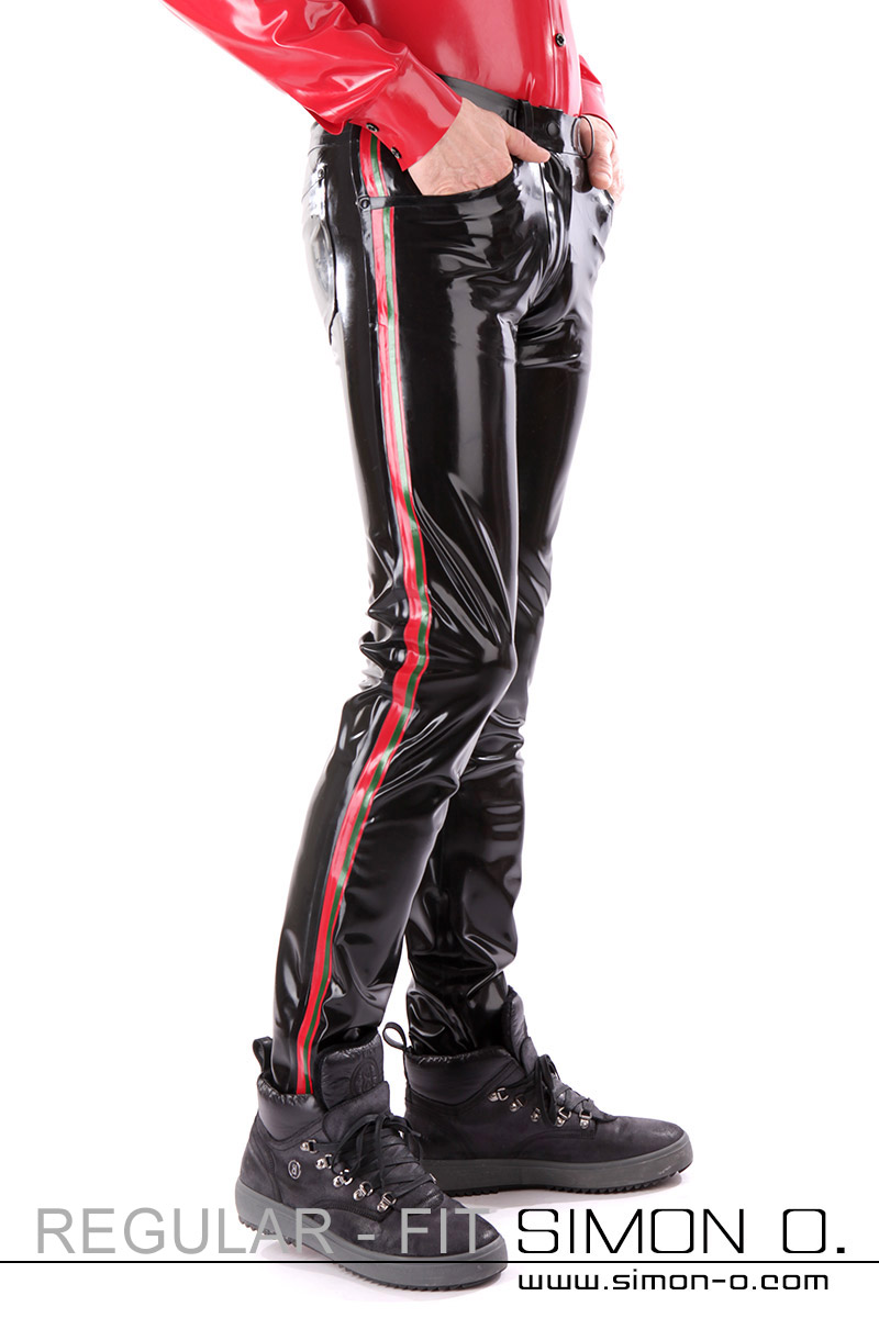 A man wears black latex jeans with red stripes on the sides and thin green stripes - seen from the front