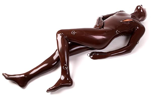A men in a shiny skin tight latex suit which oois prepared with D rings for latex bondage