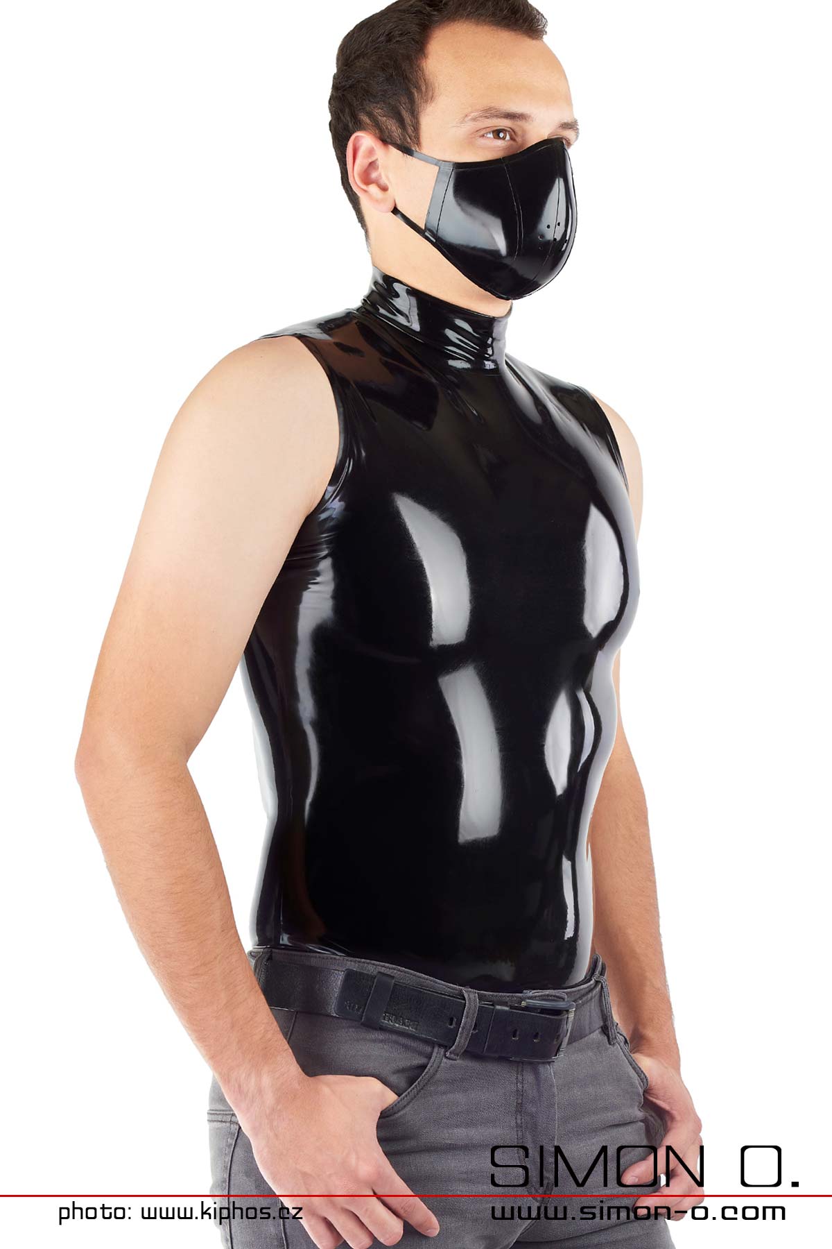 A man wears a tight sleeveless latex shirt in black with stand-up collar - seen from behind.