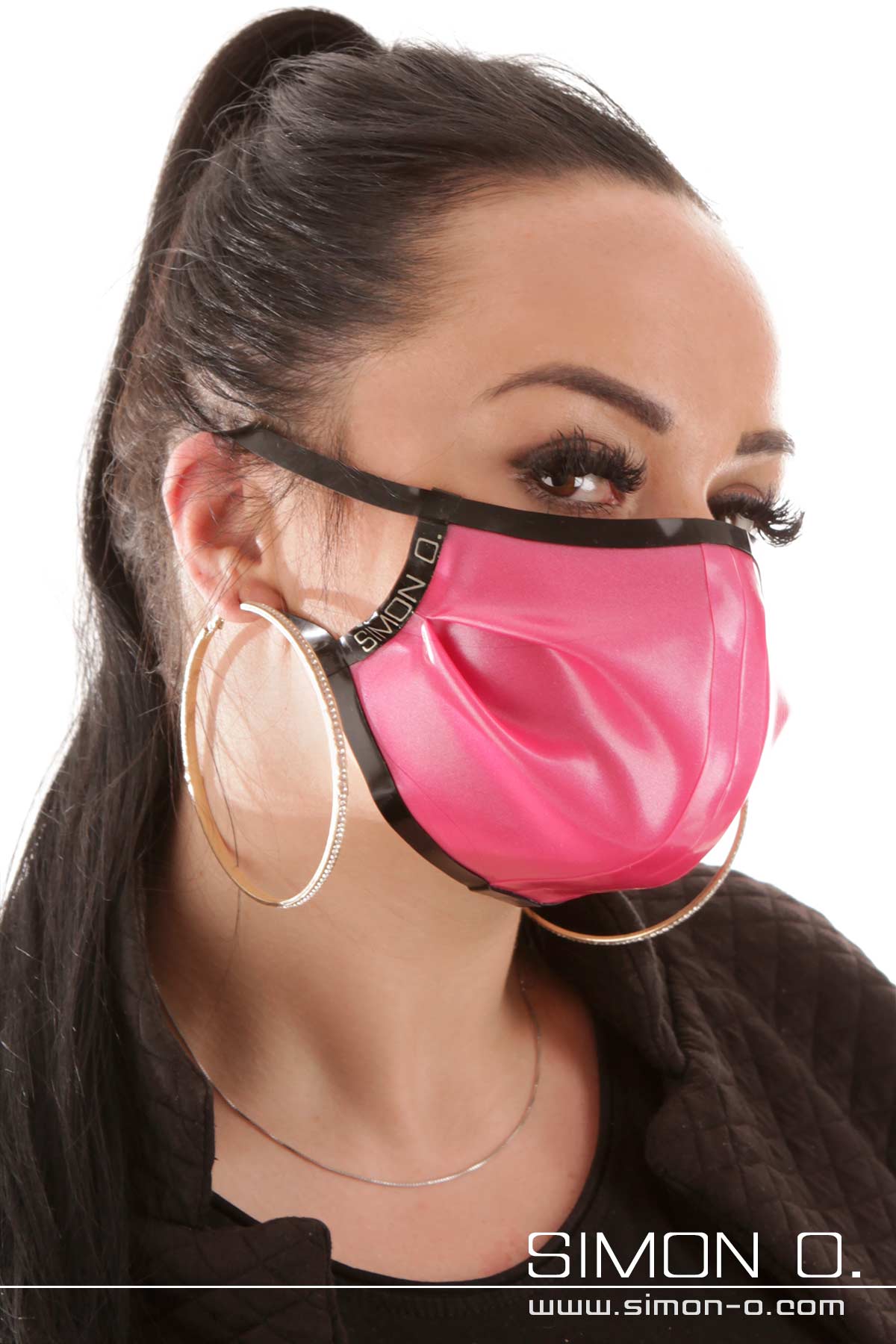 A woman is wearing a shiny latex mouth and nose guard in pink combined with black.