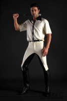 Preview: A man with a white latex shirt and a riding crop behind his head wears black and white latex breeches and riding boots.