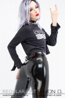 Preview: A blonde woman with a black shirt wears a shiny latex jean. Close-up of the tight buttocks area.